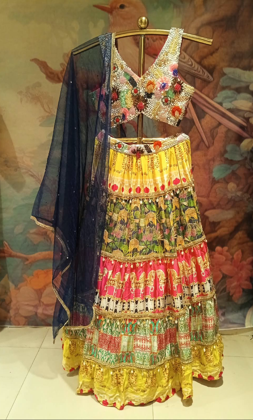 multi-colored, tiered festive Satin Silk lehenga choli printed lehenga skirt, and a navy-blue sheer dupatta.