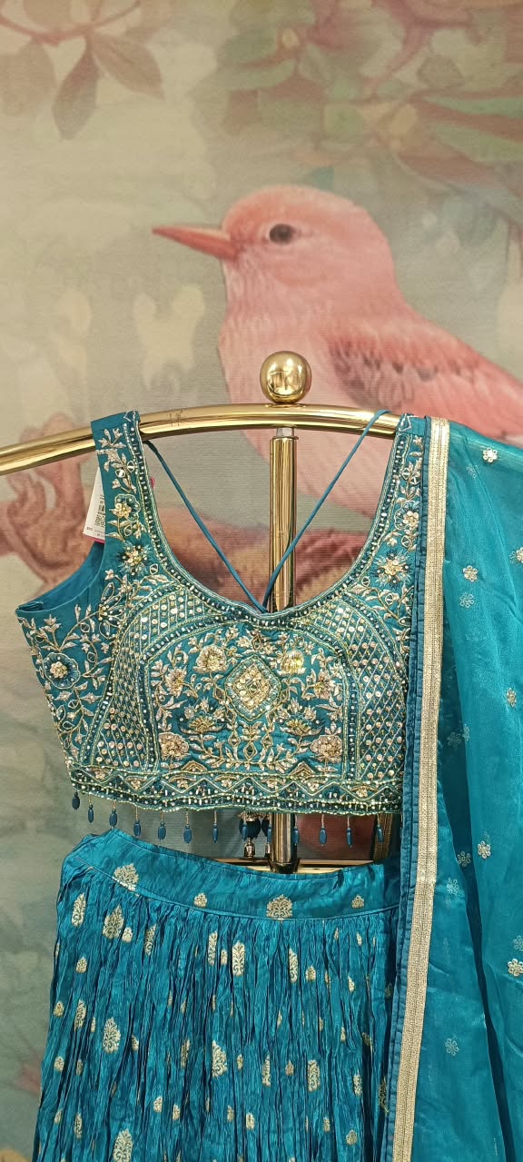 This regal three-piece teal lehenga choli royal elegance with its deep jewel tones and traditional gold artistry