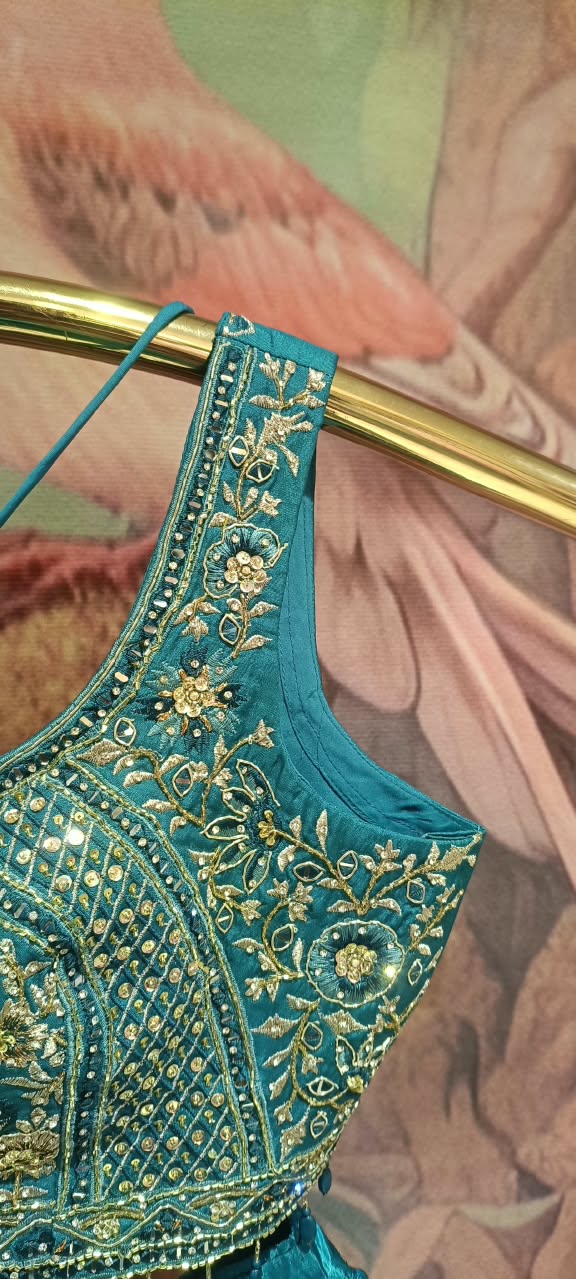 This regal three-piece teal lehenga choli royal elegance with its deep jewel tones and traditional gold artistry