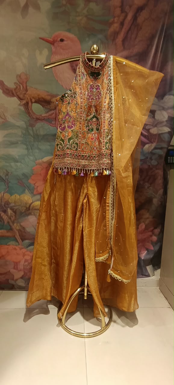 Three-piece luxury palazzo Set featuring a contemporary halter-neck tunic, heavily flared pants, and a sheer dupatta.