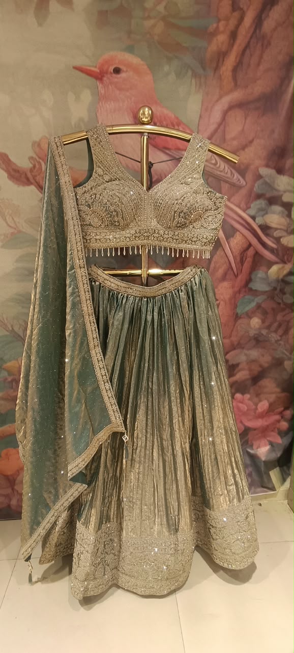 The premium event with our luxurious three-piece Metallic Sage Lehenga Choli Set.